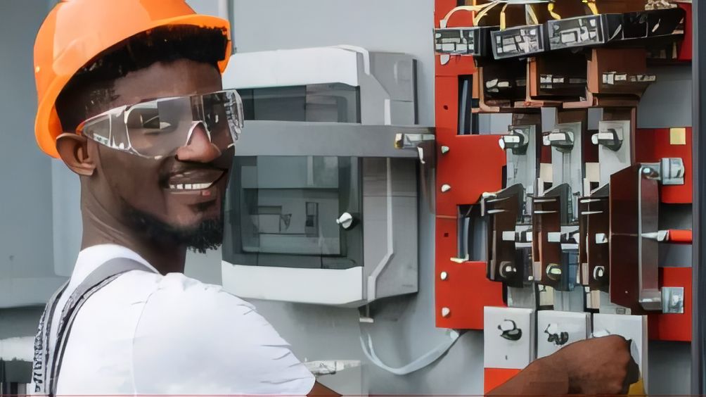 ELSIM technician in an orange hard hat and safety glasses working on switchgear inside a low-voltage control panel