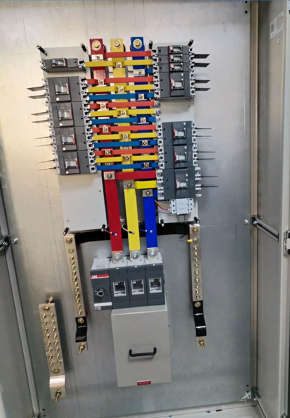 Close-up of a three-phase busbar assembly with colour-coded copper bars inside a distribution panel