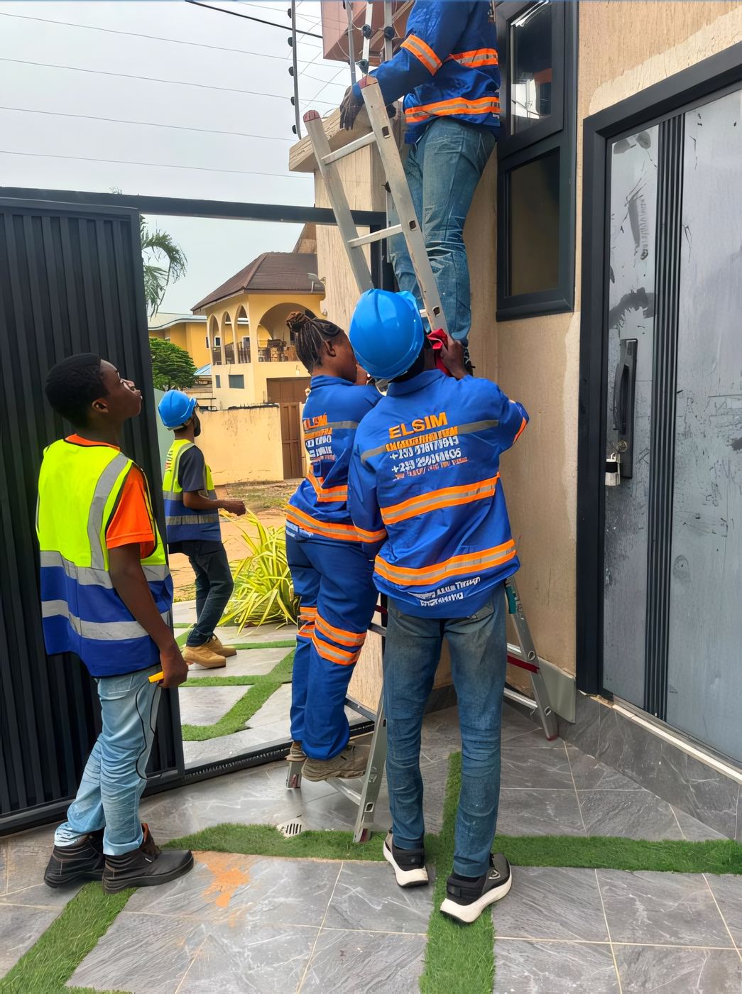ELSIM crew on a ladder installing conduit on a building facade, high-visibility strip uniforms