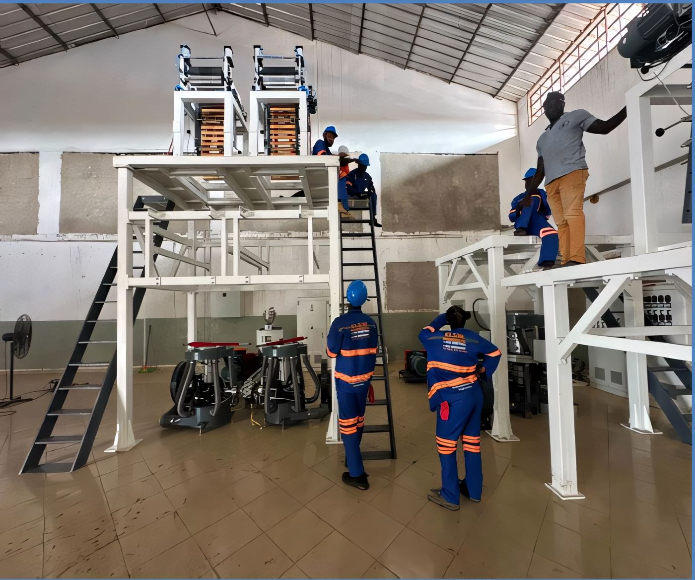 Overview of industrial machine installation in a large hall with overhead crane