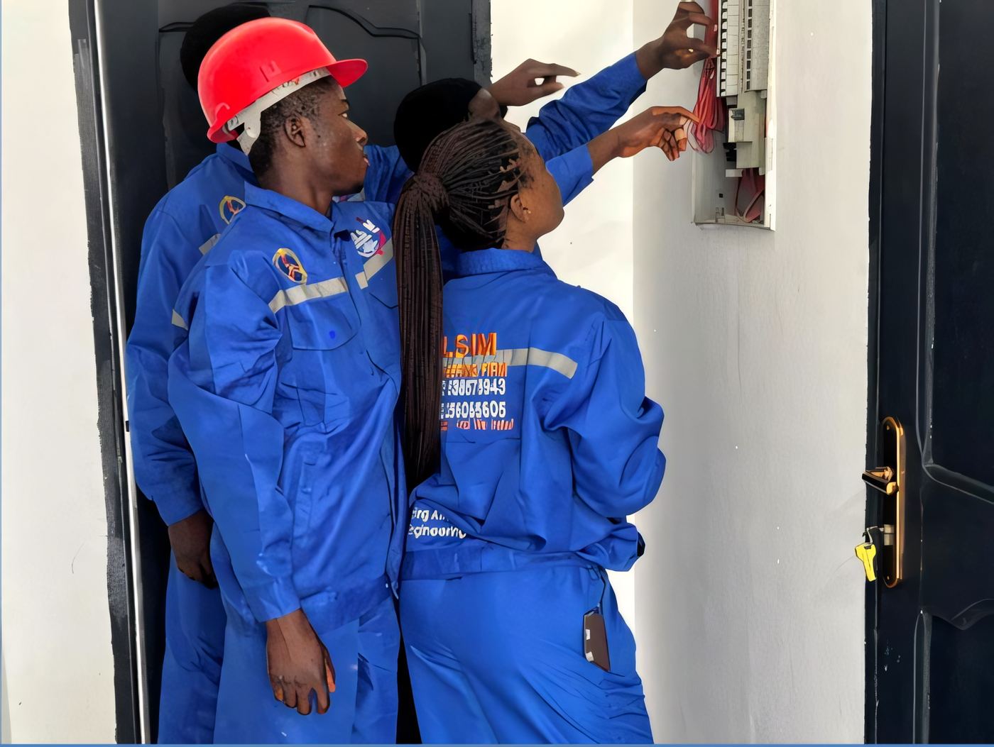 Two ELSIM technicians wiring a distribution panel inside a building doorway