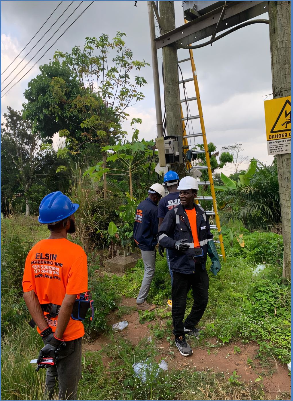 ELSIM line crew gathered at the base of a utility pole beside a danger-of-death warning sign