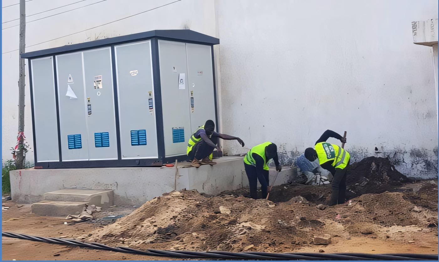 ELSIM Engineering crew in high-visibility vests excavating beside a packaged transformer kiosk substation on a West African site